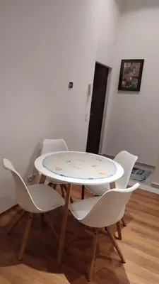 a table with white chairs and a table with a plate on it at Apartman Lena in Arandjelovac
