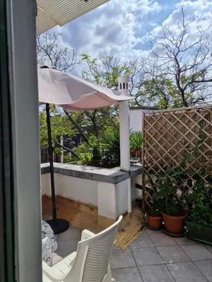a patio with an umbrella and chairs and plants at Deki & Kolet in Belgrade