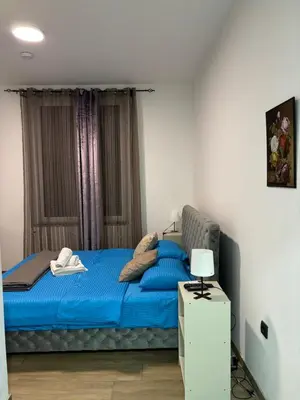 a bed with blue sheets in a room with windows at Motel Gas in Belgrade