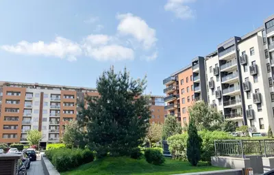 a park with a tree in front of some buildings at Cozy nest SAVADA in Belgrade