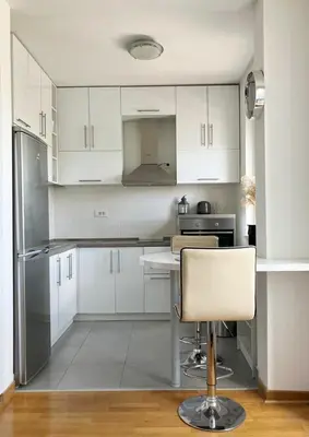 a kitchen with white cabinets and a chair in it at Cozy nest SAVADA in Belgrade