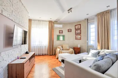 a living room with white furniture and a brick wall at Heart of Belgrade Skadarlija Apartment in Belgrade
