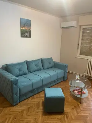a living room with a blue couch and a table at Apartman CENTAR in Titel