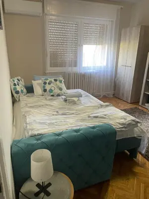 a bedroom with a large bed with a blue couch at Apartman CENTAR in Titel