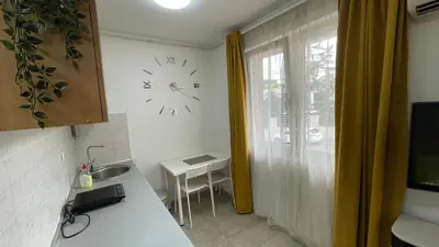 a kitchen with a clock on the wall next to a window at Voždovac Vitanovacka in Belgrade
