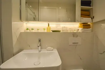 a white bathroom with a sink and a mirror at STUDIO K district (central BG+private parking) in Belgrade
