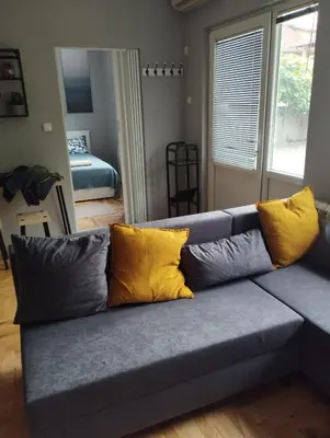 a gray couch with yellow pillows in a living room at Apartman Aleksandra in Smederevo
