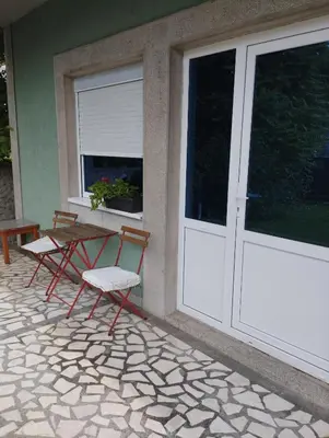two chairs and a table on a patio with a door at Apartman Aleksandra in Smederevo