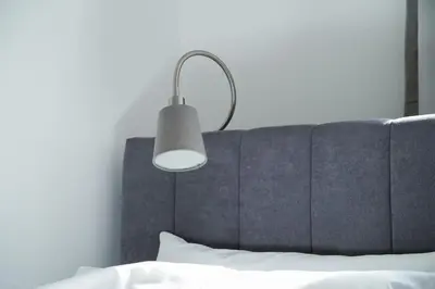 a lamp above a bed with a white pillow at Quiet Luxury Family Apt Belgrade Fortress Center in Belgrade