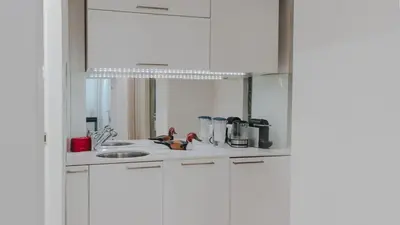 a white kitchen with a sink and a mirror at BGLAB Salon Apartment in Belgrade