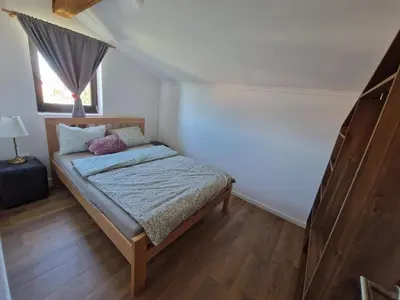 a small bedroom with a bed with a window at Che Private Rooms Banovci in Novi Banovci