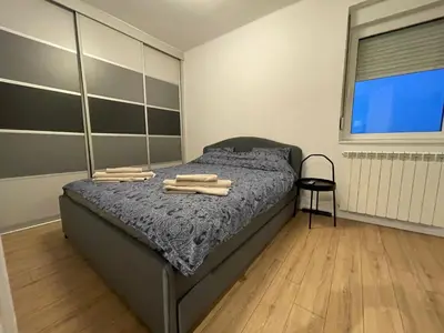 a bedroom with a bed with wooden floors and a window at New Sky Terrace in Belgrade