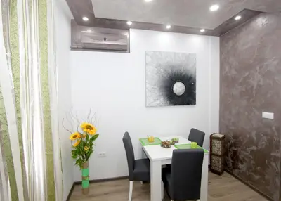 a dining room with a table and chairs and a vase of flowers at Apartment Savska in Belgrade