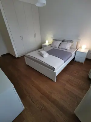 a bedroom with a bed with white cabinets and wood floors at Beograd na vodi -Belgrade Waterfront BW in Sajmište