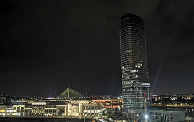 a tall building at night with a city at Beograd na vodi -Belgrade Waterfront BW in Sajmište