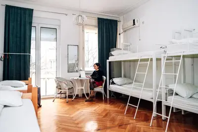 a woman sitting at a table in a room with bunk beds at Hostel Beogradjanka in Belgrade