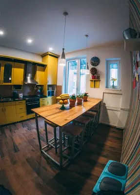 a kitchen with a wooden table and yellow cabinets at Hostel Beogradjanka in Belgrade
