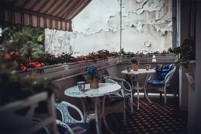 two tables and chairs in a restaurant with flowers at Hostel Beogradjanka in Belgrade