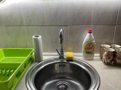a sink in a kitchen with a green basket and a bottle of soap at Hill Apartment in Belgrade