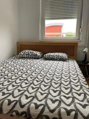 a bedroom with a bed with a large window at Hill Apartment in Belgrade