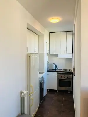 a small kitchen with white cabinets and a refrigerator at Njegoševa in Belgrade