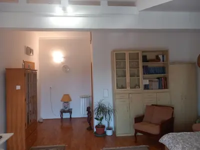 a living room with a chair and a book shelf at Cosy Rooftop studio with balcony in Belgrade