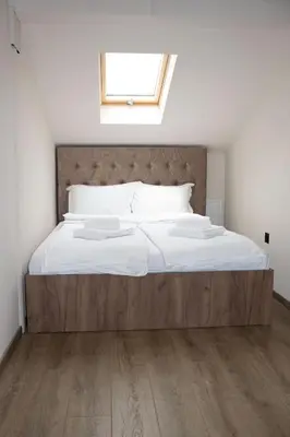 a bedroom with a large bed with white sheets and a window at ELEVENROOMS in Belgrade