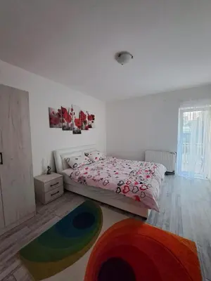 a white bedroom with a bed and a rug at Apartman Giovanni 2 in Arandjelovac