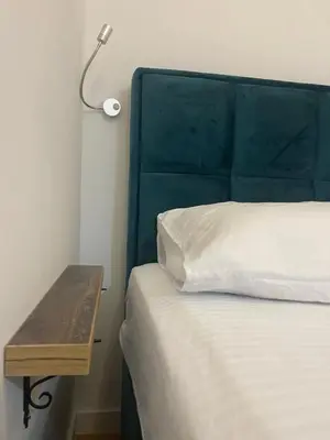 a bed with a blue headboard next to a lamp at Sofie - free parking place in the garage in Belgrade
