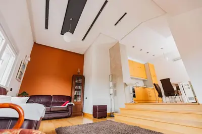 a living room with a leather couch and stairs at Apartman Kalvarija in Belgrade