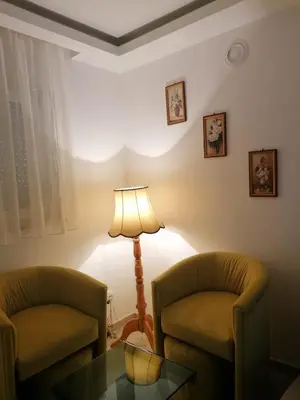 a living room with two chairs and a table and a lamp at Apartmani Glorija in Arandjelovac