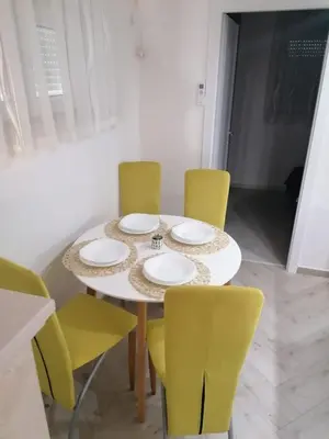 a dining room table with yellow chairs around it at Apartmani Glorija in Arandjelovac