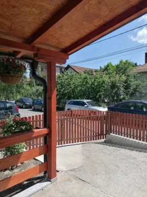 a wooden fence with a gate and cars in a parking lot at Apartmani Glorija in Arandjelovac