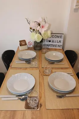 a table with white plates and a vase of flowers at Apartman Mila 21 in Zvezdara
