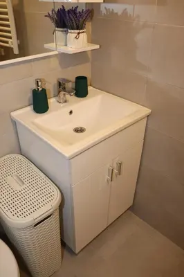 a bathroom with a white sink and a trash can at Apartman Mila 21 in Zvezdara