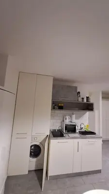 a kitchen with white cabinets and a washing machine at AVALA, New Belgrade in Fontana