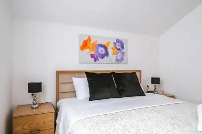 a bedroom with a bed and two night stands with lamps at Afrodita apartman in Surčin
