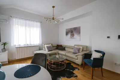 a living room with a couch and a table and chairs at Afrodita apartman in Surčin