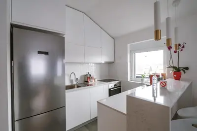 a kitchen with white cabinets and a stainless steel refrigerator at Afrodita apartman in Surčin