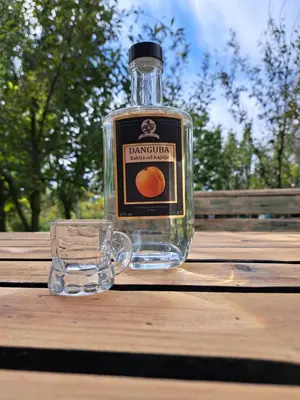 a bottle of gin sitting on a wooden table with a glass at danguba 2 in Nova Pazova