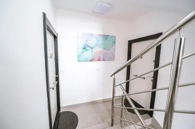a staircase in a white room with a painting on the wall at Mikonos apartman in Surčin
