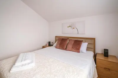 a bedroom with a bed with white sheets and brown pillows at Mikonos apartman in Surčin