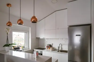 a kitchen with white cabinets and a stainless steel refrigerator at Mikonos apartman in Surčin