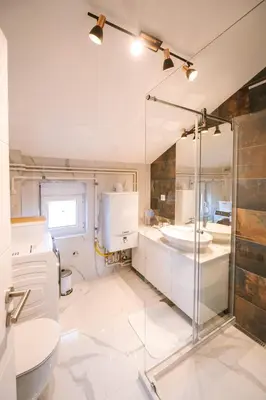 a bathroom with a glass shower and a sink at Mikonos apartman in Surčin