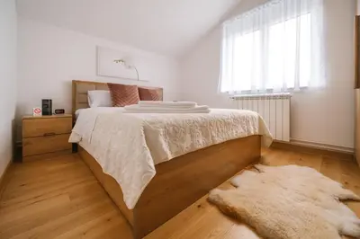 a bedroom with a large bed and a rug at Mikonos apartman in Surčin