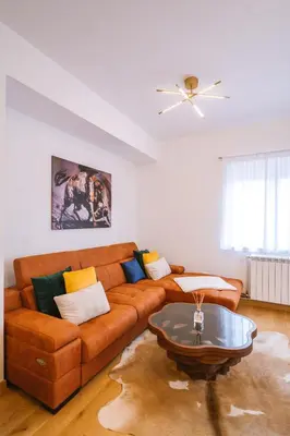 a living room with a brown couch and a coffee table at Mikonos apartman in Surčin