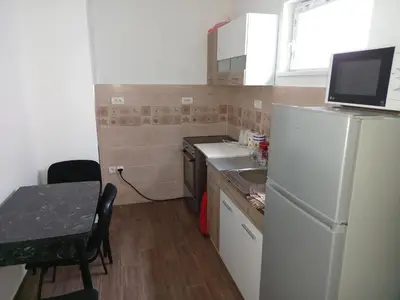 a small kitchen with a white refrigerator and a table at Itaka - Belgrade City Center in Belgrade