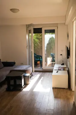 a living room with a bed and a sliding glass door at Dukes Apartment in Belgrade