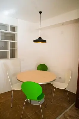 a table and four green chairs in a room at Dukes Apartment in Belgrade
