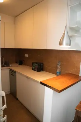 a kitchen with white cabinets and a wooden counter top at Dukes Apartment in Belgrade